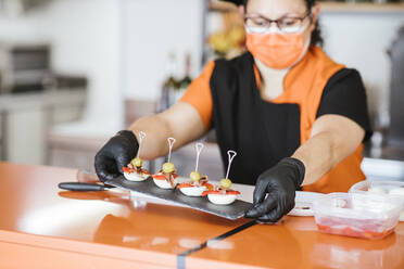 Köchin hält Servierbrett am Tresen in einer Cafeteria - LJF02240