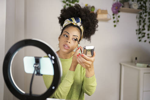 Female influencer giving make-up tutorial through vlogging at home - JCCMF03126