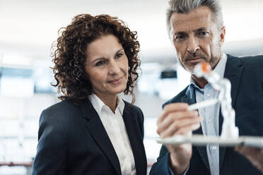 Businessman checking robot arm while standing by colleague in industry - MOEF03734