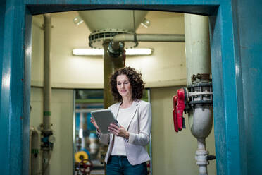 Businesswoman using digital tablet while standing at doorway - MOEF03825