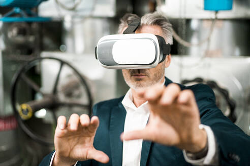 Businessman gesturing while using virtual reality headset at workshop - MOEF03829