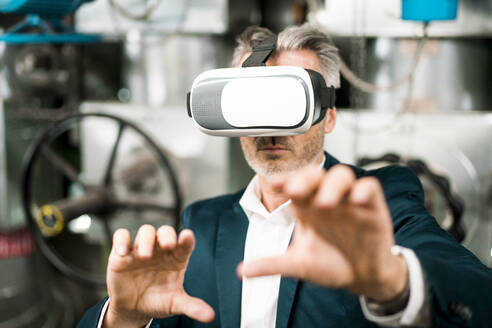 Geschäftsmann gestikuliert bei der Verwendung eines Virtual-Reality-Headsets in einem Workshop - MOEF03829