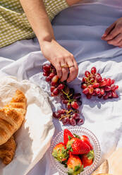 Hohe Winkel der Ernte weiblich mit reifen Trauben haben Picknick mit Croissant und Erdbeeren mit Focaccia - ADSF26966