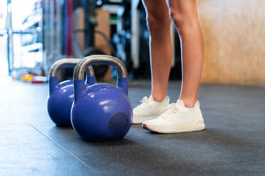 Cropped unrecognizable determined female athlete in sportswear standing resting after during functional training with weights on floor in gym - ADSF27092