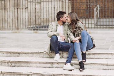 Couple kissing each other while sitting on steps - LJF02261