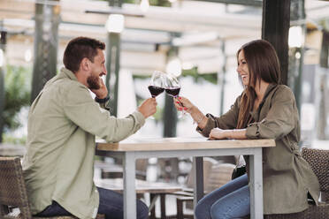 Mid adult couple toasting wine while sitting at bar - LJF02264