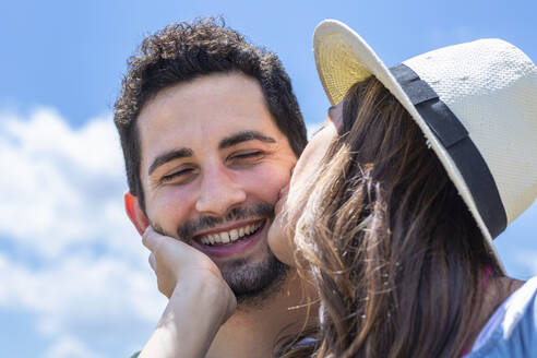 Freundin mit Hut küsst ihren Freund an einem sonnigen Tag - EIF01624