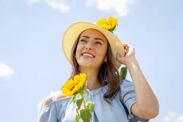 Glückliche Frau mit Hut und Sonnenblumen an einem sonnigen Tag - EIF01639