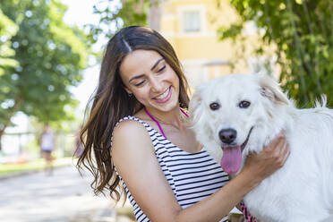 Young woman smiling while stroking at dog - EIF01671