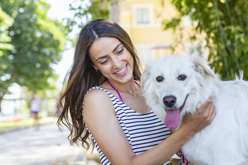 Junge Frau lächelt und streichelt ihren Hund - EIF01671