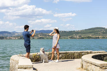 Freund fotografiert Freundin mit Hund auf der Seebrücke - EIF01674