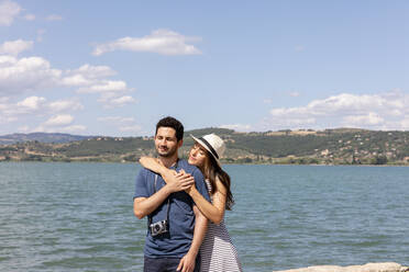 Woman embracing boyfriend from behind in front of Lake Trasimeno - EIF01676