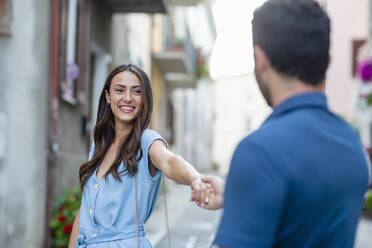 Young woman smiling while holding hand of boyfriend - EIF01744