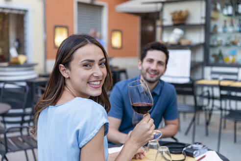 Glückliche Frau trinkt Wein mit ihrem Freund in einem Straßencafé - EIF01750