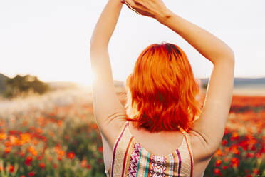 Redheaded woman with hands raised at sunset - MRRF01276