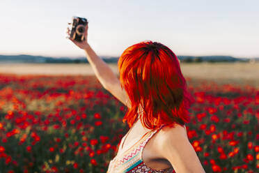 Frau macht Selfie durch Kamera auf Mohnfeld - MRRF01277