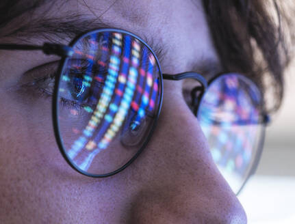 Male teenage scientist with DNA test results reflection on eyeglasses - ABRF00902