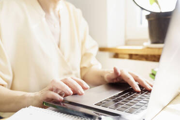 Reife Frau, die einen Laptop benutzt, während sie im Büro zu Hause arbeitet - KMKF01713