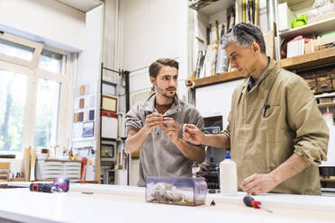 Male colleagues working at workshop - MEUF03556