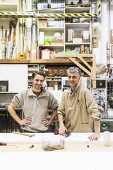 Smiling owner and male craftsperson at workshop - MEUF03564