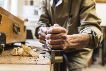 Mature male craftsperson sawing wood at workshop - MEUF03571