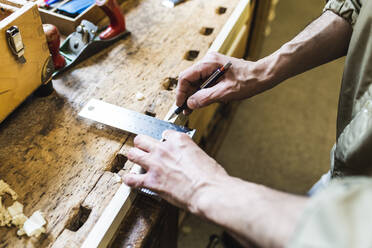 Male carpenter measuring with ruler at workshop - MEUF03572