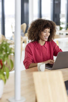 Lächelnde Geschäftsfrau mit Laptop bei der Arbeit im Büro - PESF02974
