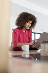 Weibliche Fachkraft lächelt bei der Verwendung eines digitalen Tablets im Büro - PESF02983