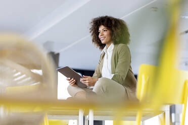 Thoughtful female professional with digital tablet sitting at office - PESF03030