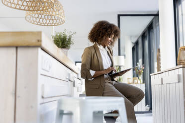 Afro businesswoman using digital tablet sitting in office - PESF03051