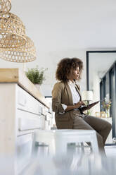 Young businesswoman looking away while sitting with digital tablet in office - PESF03053