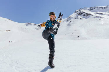 Content male athlete in sports clothes having fun with raised leg while looking at camera against Sierra Nevada in Spain - ADSF27155