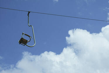 Empty ski lift chair against sunny blue sky - FSIF05734