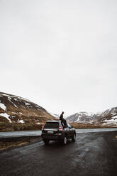 Man on car on tranquil road in cold highlands - ADSF27277