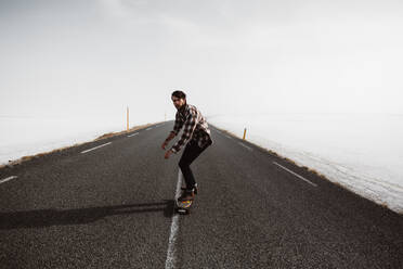 Mann fährt Skateboard auf einer Landstraße - ADSF27290