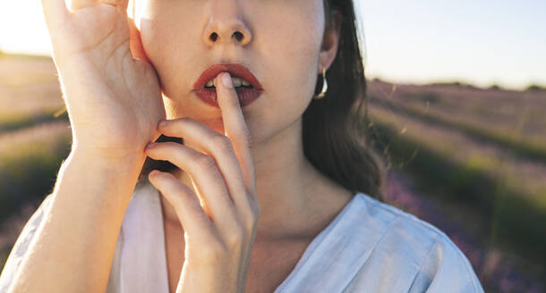 Junge Frau mit Finger auf den Lippen auf einem Feld - JCCMF03192