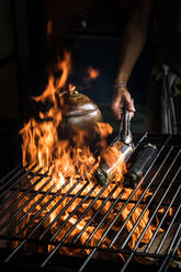 Hohe Winkel der Ernte Koch Kochen köstliche exotische Mischung aus Garnelen und Gemüse in Bananenblatt und gebackene Kokosnuss auf Grill im Restaurant gewickelt - ADSF27306