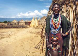 Frau in traditioneller Kleidung lächelt mit ihrem Jungen in einem Dorf des Arbore-Stammes, Omo-Tal, Äthiopien - ADSF27319