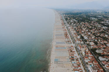 Luftaufnahme eines riesigen Strandes mit vielen Sonnenschirmen in Viareggio, Italien. - AAEF09614