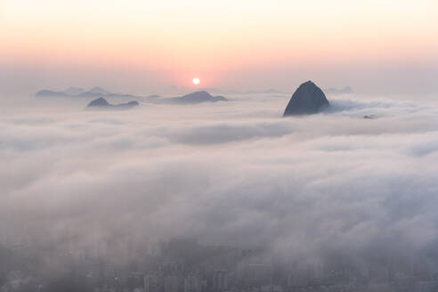 Luftaufnahme über eine Decke von niedrigen Wolken von Sugarloaf Mountain Peak bei Sonnenaufgang in Rio de Janeiro, Brasilien - AAEF09660