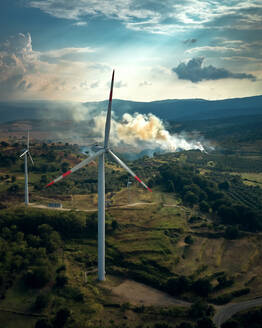 Luftaufnahme eines modernen Windparks mit einem Feuer im Hintergrund, Palermiti, Kalabrien, Italien. - AAEF09722