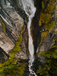 Aerial view of a steep majestic waterfall hidden by the forest in Val di Mello, Lombardy, Italy. - AAEF09736