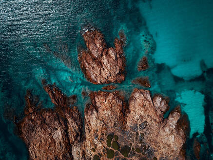 Luftaufnahme einer rötlichen, abgelegenen Klippe, umgeben von spektakulärem türkisfarbenem Wasser in der Nähe der Isola Rossa, Sardinien, Italien. - AAEF09739