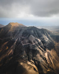 Luftaufnahme einer schmalen Straße in der Nähe von Cofete an einem bewölkten Tag, Fuerteventura, Kanarische Inseln, Spanien. - AAEF09800