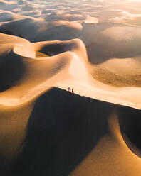 Aerial view of two persons walking on a sand dune ridge in a desert valley near Maspalomas, Las Palmas islands, Canary Island, Spain. - AAEF09807