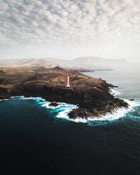 Aerial view of Farol de Sardinia, a beautiful lighthouse along a scenic coastline with wild cliffs facing the Atlantic Ocean on Gran Canaria, Canary Islands, Spain. - AAEF09811