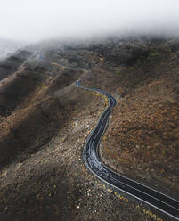 Aerial view of an empty road driving along a volcanic hillside near Mogan, Canary Islands, Spain. - AAEF09836