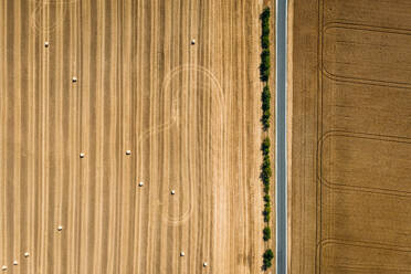 Abstrakte Luftaufnahme von Strohballen auf einem durch eine Straße unterteilten Feld in Schernberg, Deutschland. - AAEF09850