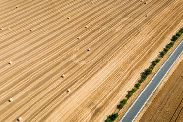 Abstrakte Luftaufnahme von Strohballen auf einem durch eine Straße unterteilten Feld in Schernberg, Deutschland. - AAEF09855