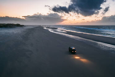 Luftaufnahme eines Wohnmobils, das über den Strand der Insel Terschelling, Friesland, Niederlande, fährt. - AAEF09874